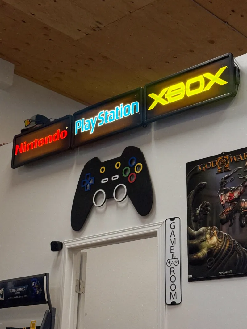 Neon Nintendo, PlayStation and Xbox signs above a controller-shaped wall decal