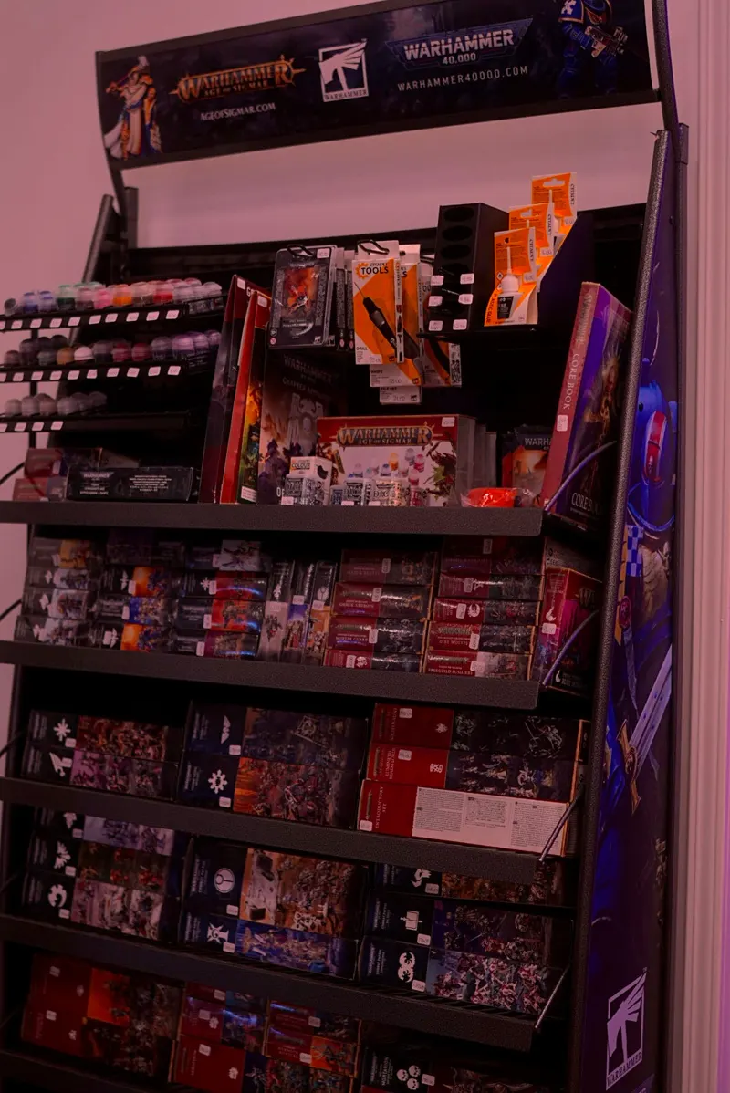 A Warhammer rack of hobby paints, brushes and boxed miniatures